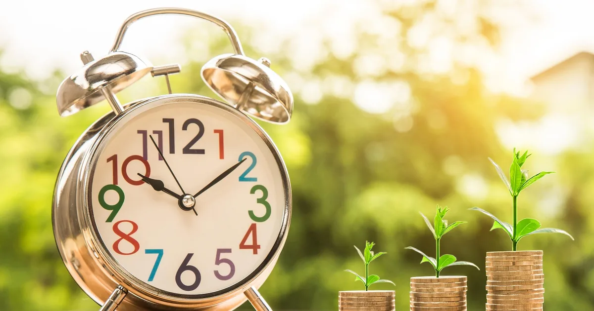 Wekker naast groeiende muntstapels symboliseert het rente-op-rente-effect