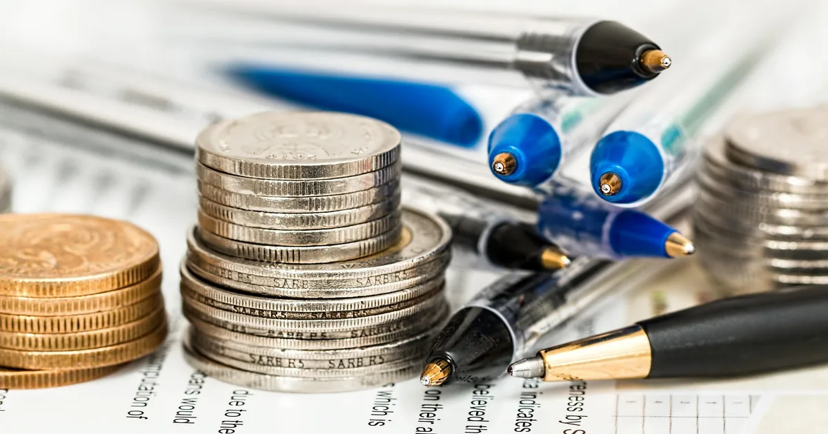 Muntstapels en pennen op financieel overzicht om geld te besparen